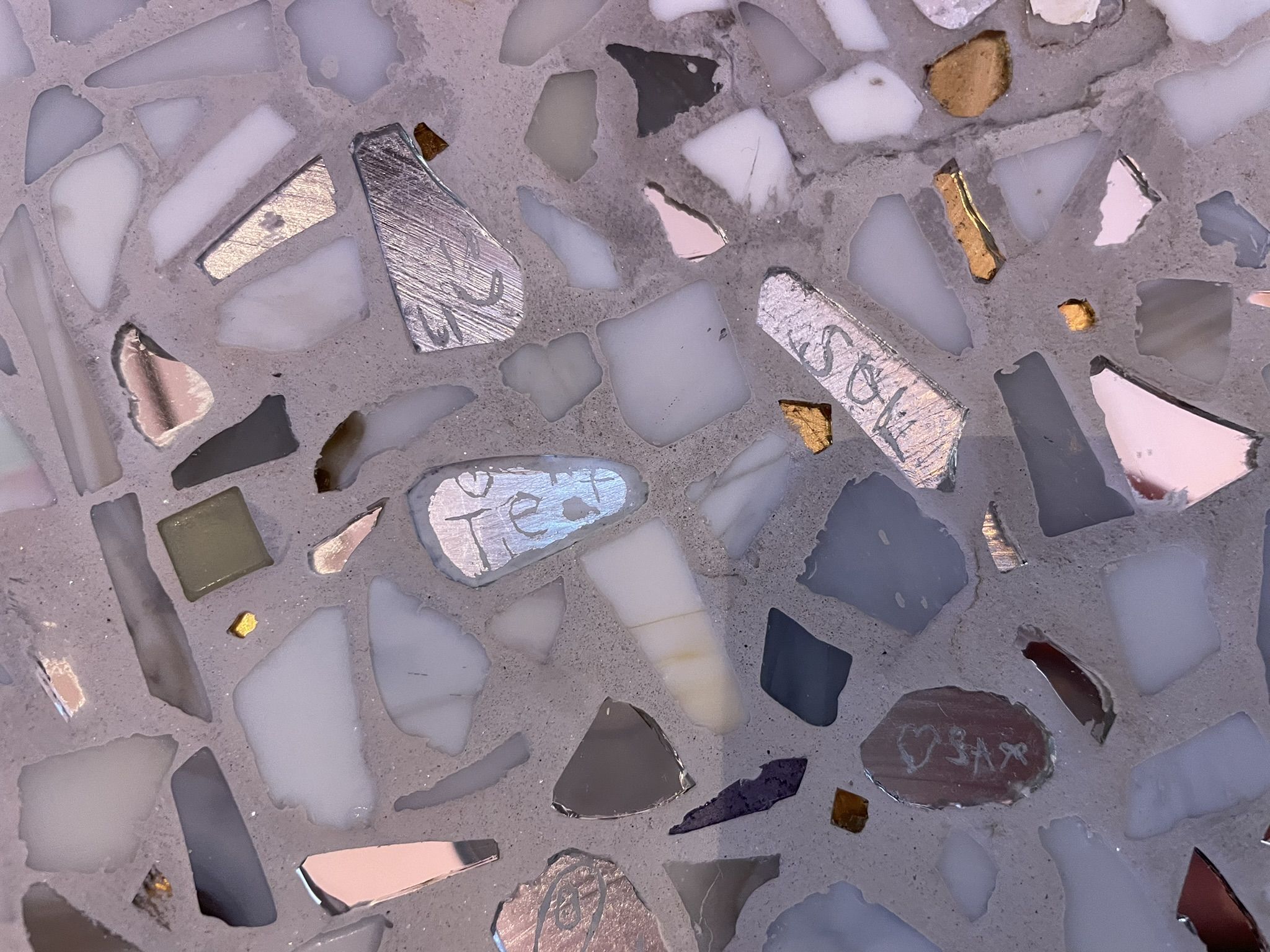 Nærbilde av fliser montert på benk, med tekst laget av barn.